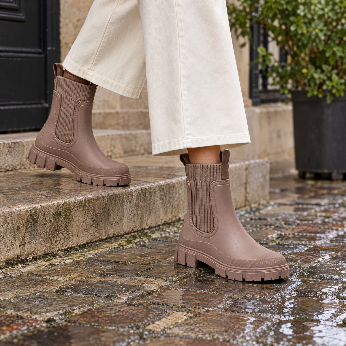 The Cherry Drop rain boot in Cherry Stone, on a wet cobbled street