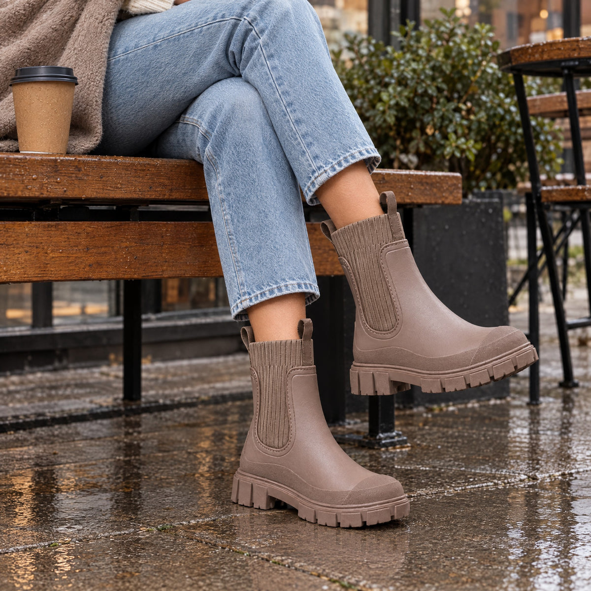 The Cherry Drop rain boot in Cherry Stone, at a cafe on a drizzly day